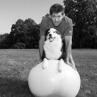 therapist helping his dog exercise on a yoga ball