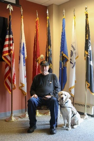 VetDog Puppy, Ace, sitting beside his Vietnam War veteran, Robert