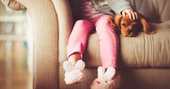 little girl and her dog sitting together on a couch