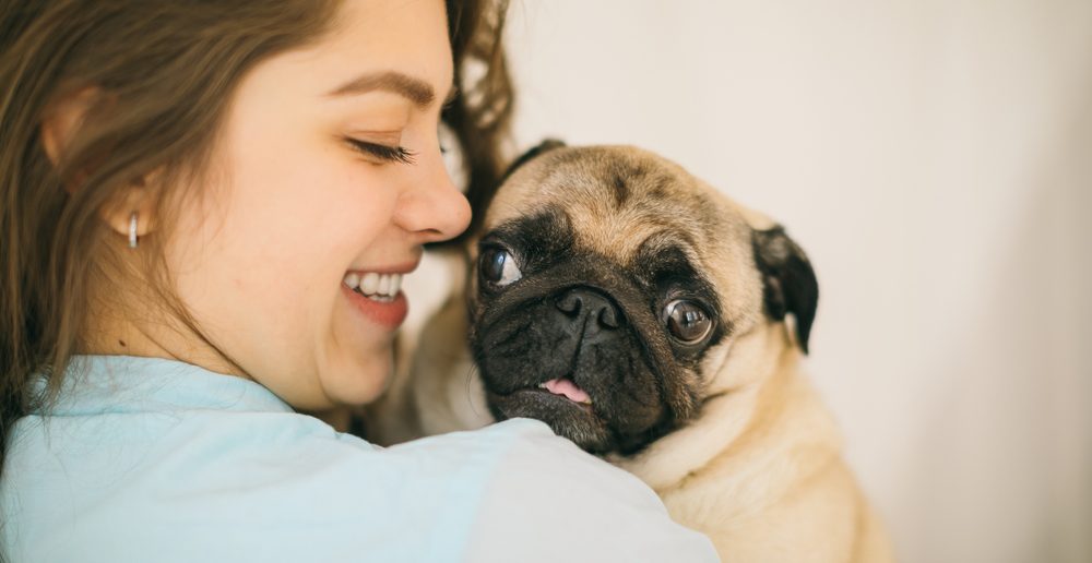 girl hugging her pug dog