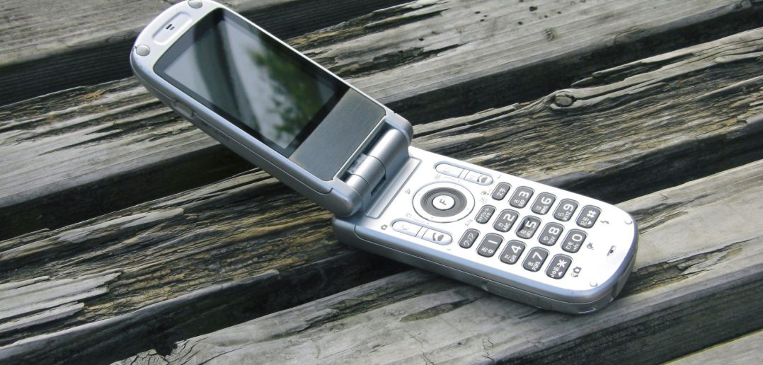 mobile flip phone sitting open on a picnic table