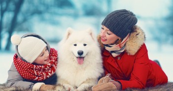 mother and son with white Samoyed dog in winter